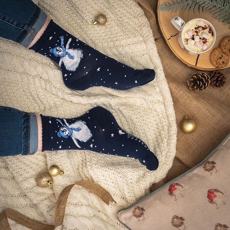 Calze natalizie da donna decorate con un pinguino con sciarpa e cuffia su sfondo indaco