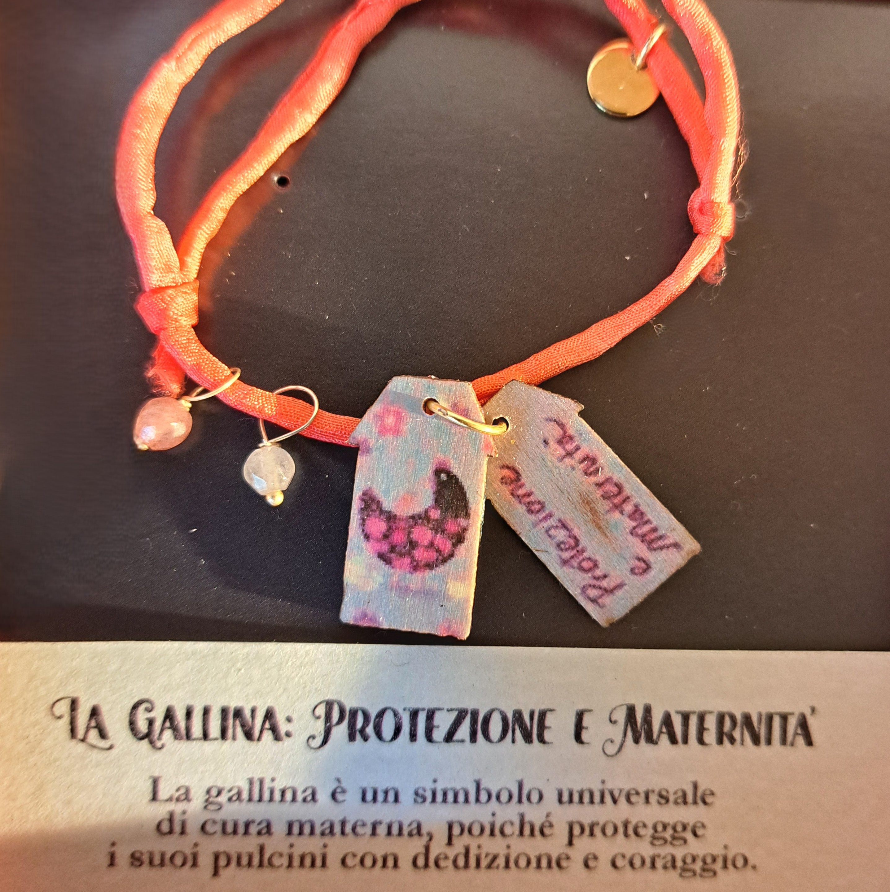 Braccialetto in seta decorato con pietre e casette di legno laccato raffiguranti una gallina con dedica “Protezione e maternità