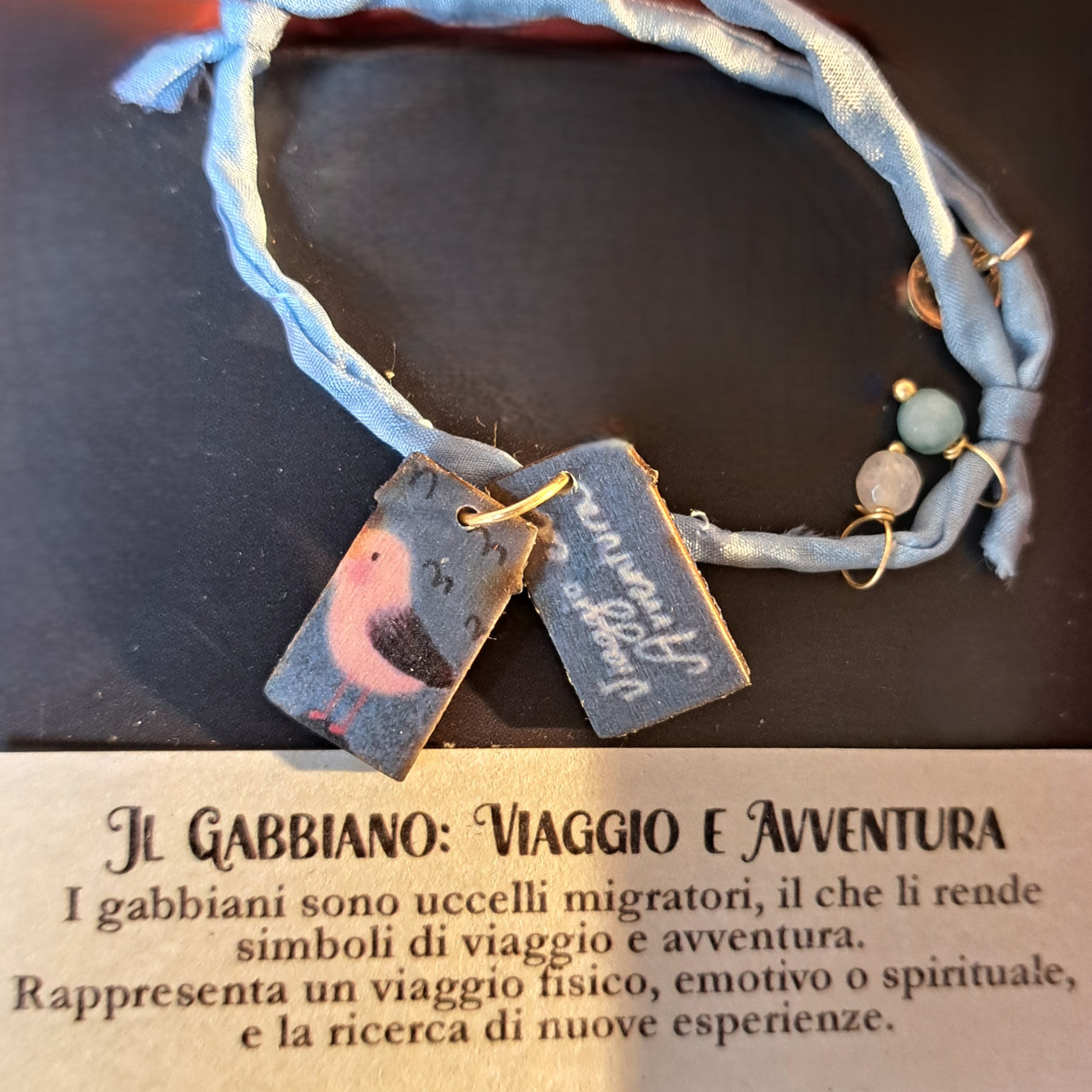 Braccialetto in seta decorato con pietre e casette di legno laccato raffiguranti un gabbiano con dedica “Viaggio e avventura