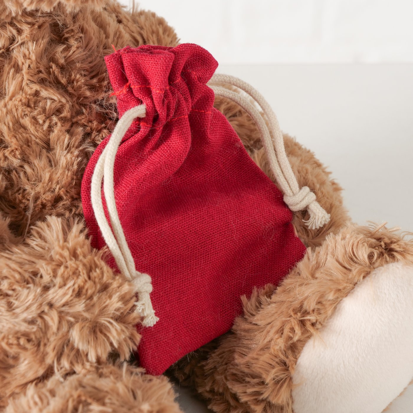 Peluche morbido a forma di orsetto marrone con sacco rosso