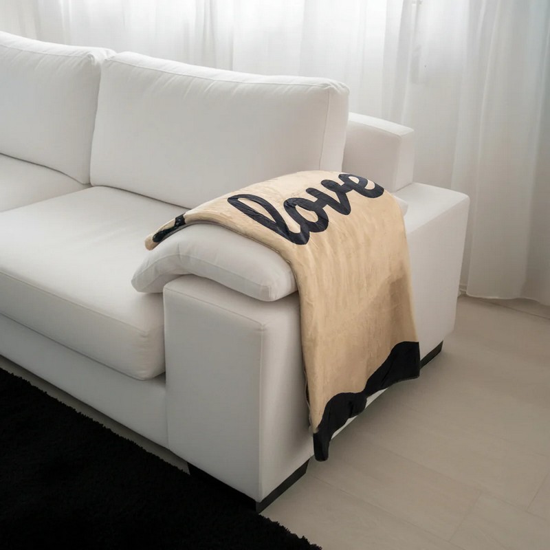 Coperta in flanella color sabbia decorata con bordi neri e scritta “All you need is love”, una caldissima idea regalo Natale o coppie