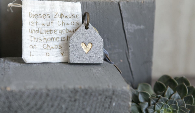 Portachiavi con sasso a forma di casetta decorato con cuore, contenuto in un sacchettino di cotone