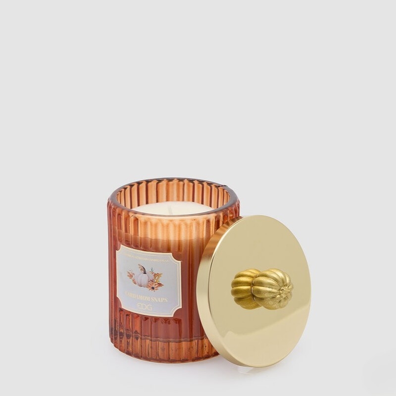 Candela profumata autunnale al cardamomo contenuta in un barattolo di vetro arancione con coperchio con zucca, utilizzabile da sé una volta esaurita la candela, perfetta come idea regalo autunno