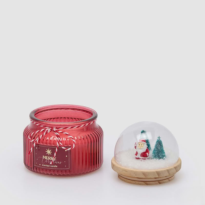 Candela in vetro rosso profumata al sidro di mele con miele, con coperchio a forma di cupola con paesaggio natalizio in legno, neve e campanelle
