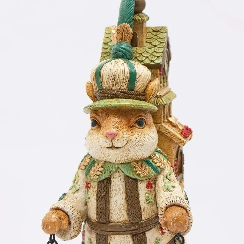 Scoiattolo da appoggio in resina con casetta con orologio in spalla, cappello, vestito elegante e pigne in mano, perfetto come decoro originale di Natale